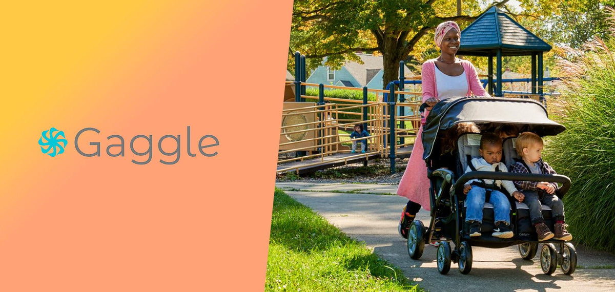 Woman pushing multi-child stroller with toddlers at a playground in sunny park