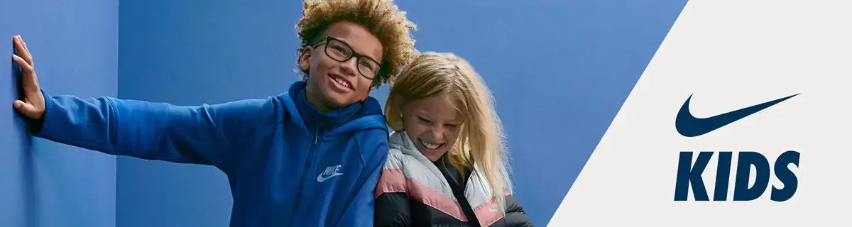 Smiling kids wearing Nike jackets in a modern blue room, Nike Kids logo displayed.