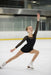 Girl's black figure skating dress shown worn by a child performing on an indoor ice rink.