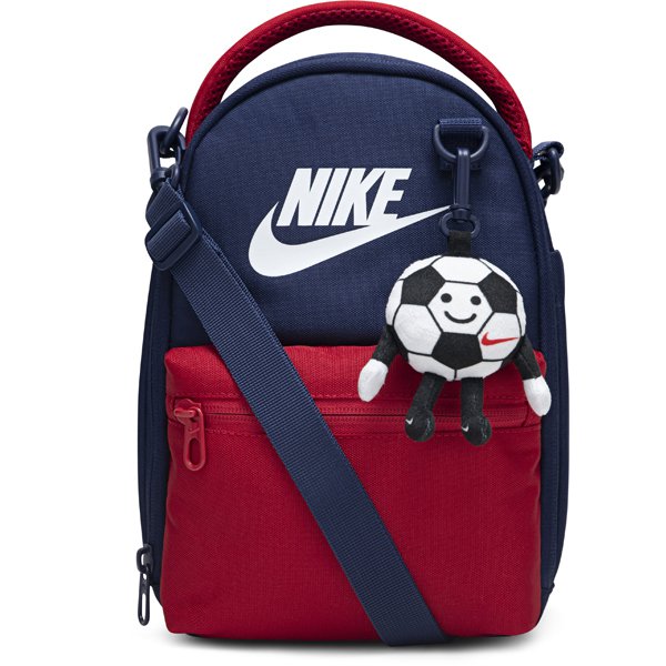 Nike kids' navy and red crossbody bag with a smiling soccer ball keychain on the front pocket.