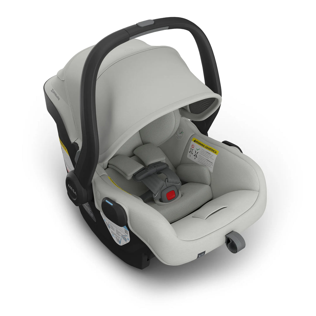 Infant car seat carrier with light grey fabric, padded harness, and black handle