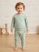 Toddler wearing matching mint green bear print pajama set standing on wooden floor.