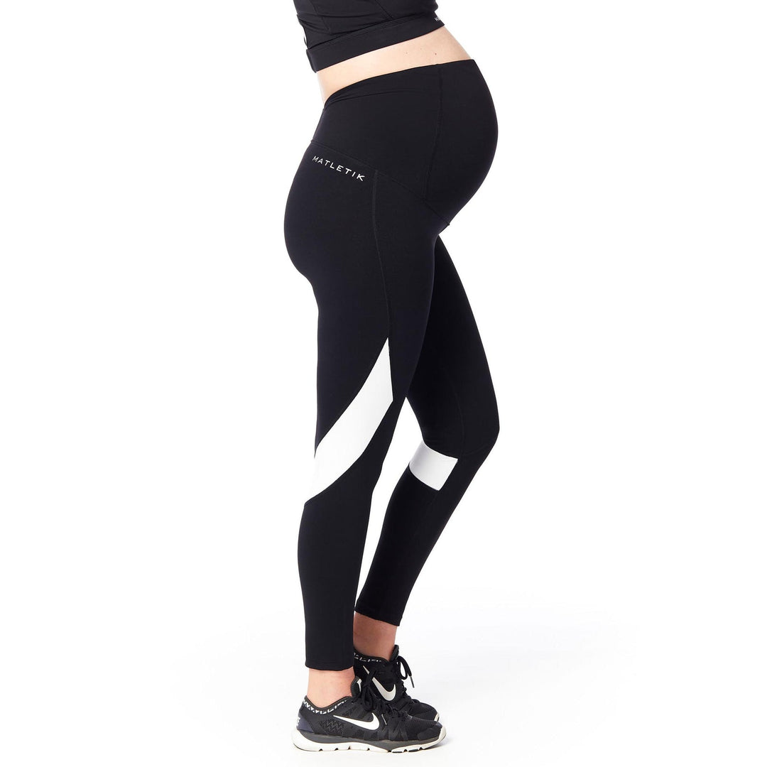 Matletik maternity leggings in black with white accents, shown on a pregnant woman standing sideways.