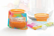 Baby Brezza reusable food pouch filled with pureed food, shown on a clean countertop with caps and funnel.