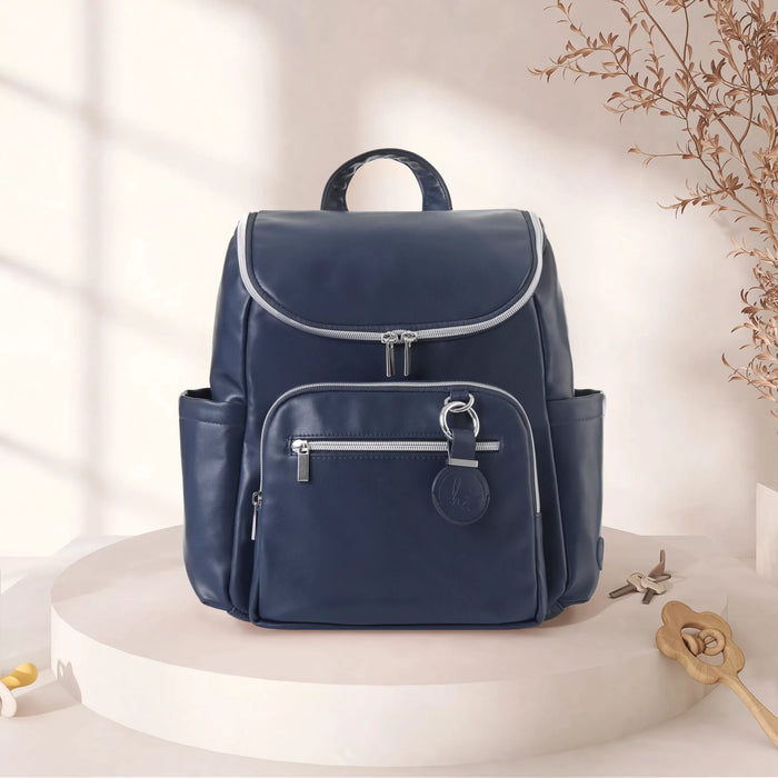 Navy blue diaper backpack with silver zippers on a minimal beige background