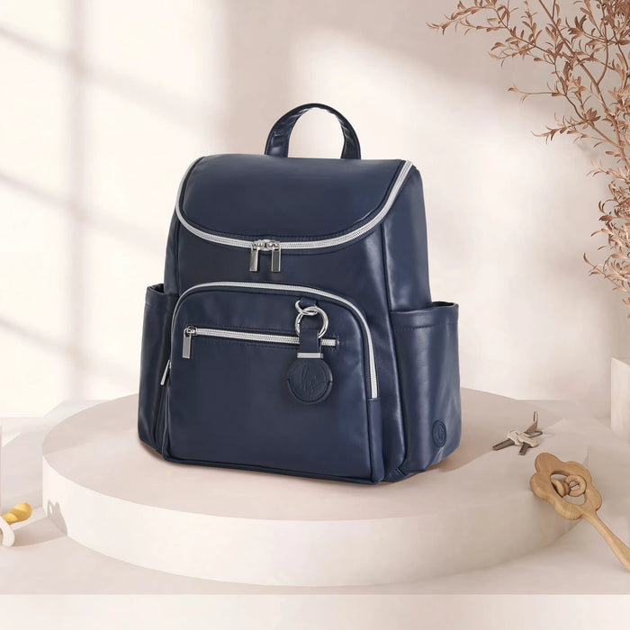 Navy blue diaper backpack with silver zippers on a round display, stylish and practical design