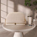 Beige quilted diaper bag with gold zippers on table, next to tumbler and smartphone.