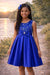 Navy blue party dress with jeweled bow detail, worn by a girl outdoors by a lake at sunset.