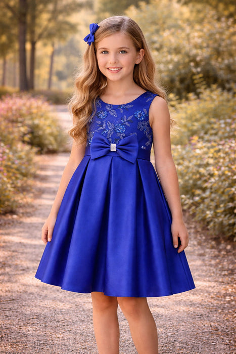 Navy blue party dress with floral sequins and bow, worn by a girl outdoors on a sunny path.