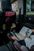 Car seat organizer hanging on front seat with books, child seated in rear reading a picture book.