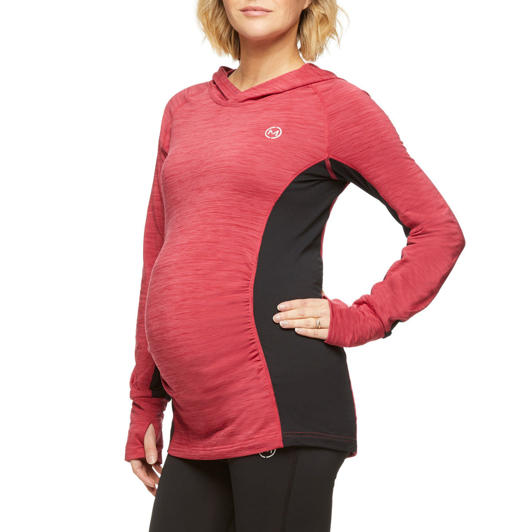 Maternity activewear hoodie in red and black shown on a pregnant woman standing against a white background.
