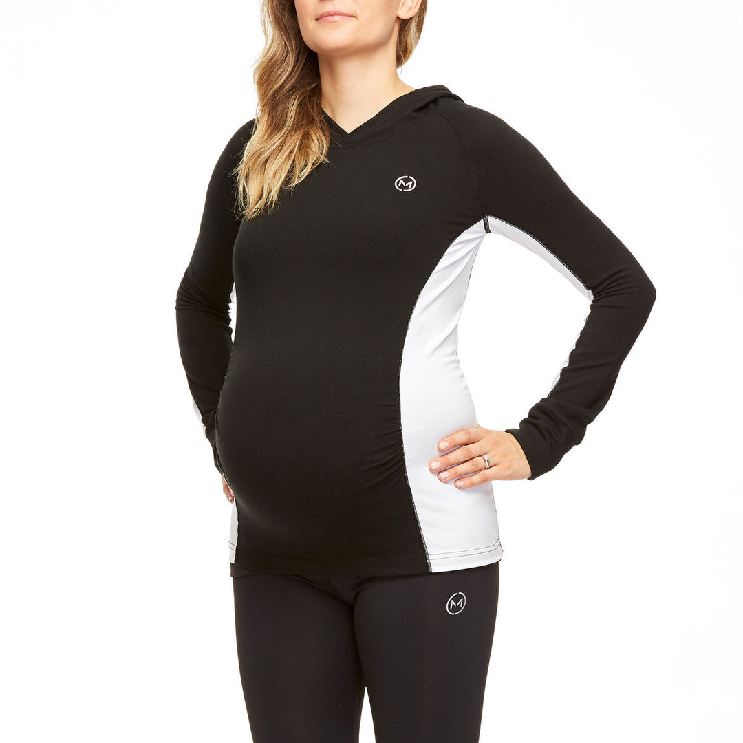 Maternity activewear hoodie in black and white worn by a pregnant woman, shown from the side.