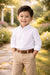 Elevate Oxford Shirt White worn by a young boy outdoors, hands in pockets, with garden background.