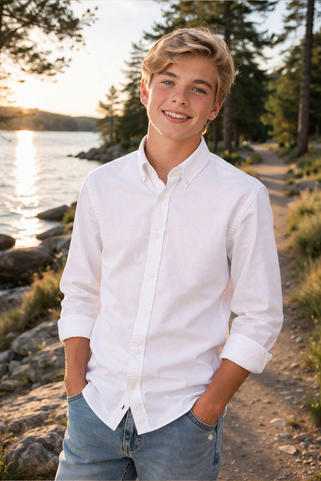 Elevate Oxford Shirt white shown on a boy standing outdoors by a lake at sunset.