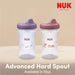 NUK Advanced Hard Spout sippy cups in purple and pink, shown on a beige surface.