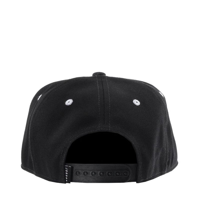 Black snapback cap shown from the back with adjustable closure and white eyelets on a white background.