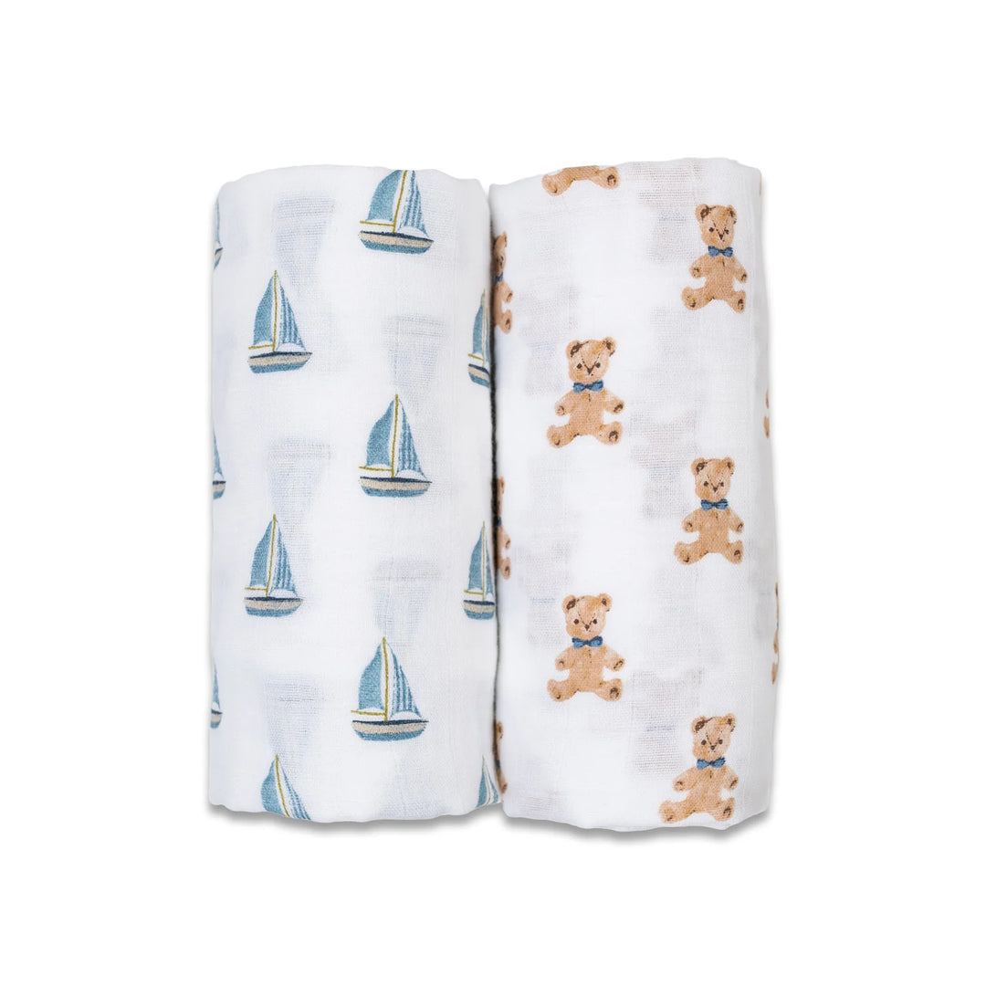 Two baby muslin blankets, one with sailboat print and one with teddy bear print, on white fabric