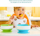 Toddler using silicone suction bowl and spoon set while eating in a high chair.