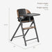 Modern baby high chair with wood accents, black seat, and tray, shown with dimensions.