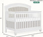White wooden baby crib with upholstered headboard, slatted sides, and size dimensions shown