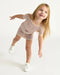 7AM Hug Me Ribbed Knit Dress Ash Rose shown on a smiling child posing playfully against a white background.