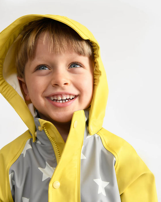 7AM rain coverall in yellow and grey with stars, worn by a smiling child against a white background.
