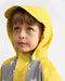 7AM rain coverall shown on a child, featuring a yellow hood and grey star-patterned fabric.