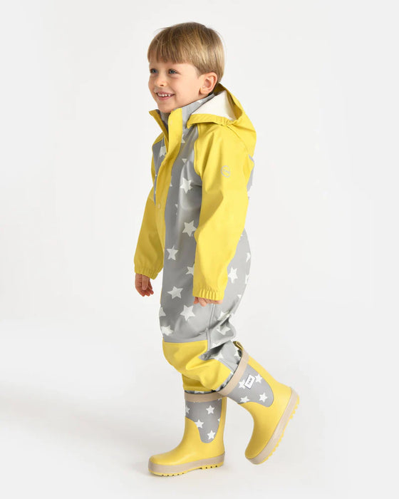 7AM rain coverall with gray star pattern and yellow accents worn by a child standing indoors.