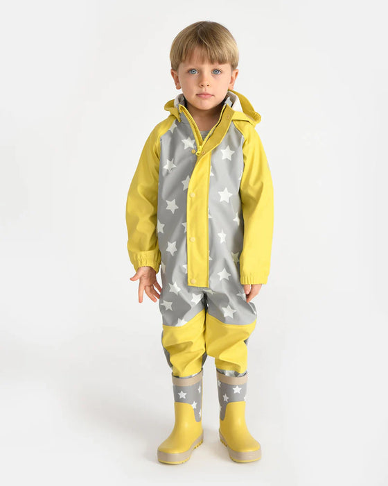 7AM rain coverall shown on a child standing, featuring yellow and grey star pattern with matching boots.