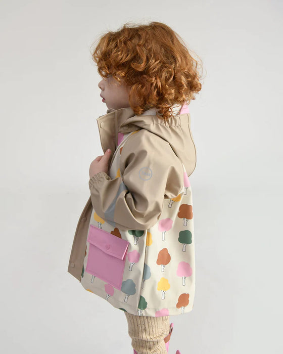 7AM rain jacket with colorful tree print, shown on a child standing in profile indoors.