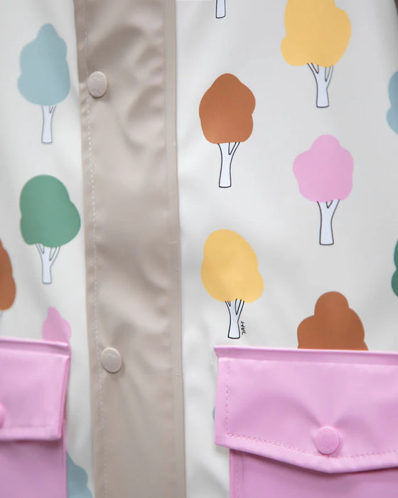 Kids rain jacket with colorful tree pattern and pink pockets shown in close-up view.