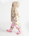 Child wearing a beige hooded rain jacket with colorful tree pattern, matching pants and pink boots.