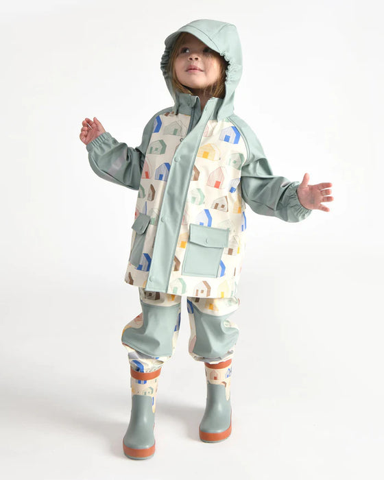 Child wearing a pastel rain jacket set with hood and boots on a plain white background.