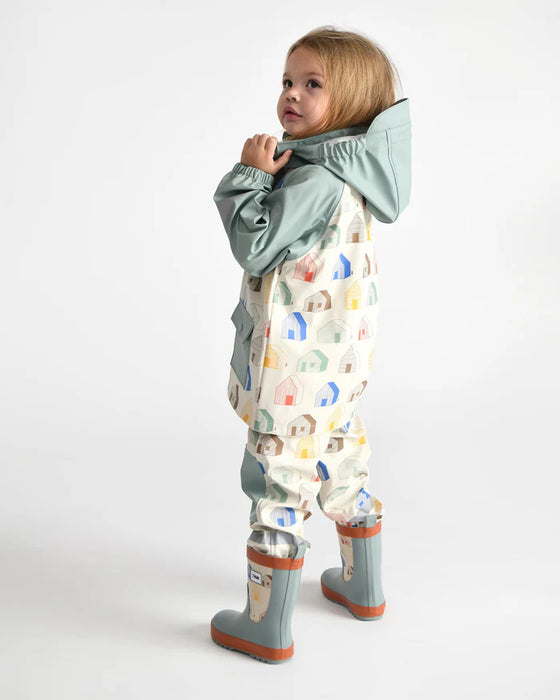 7AM rain jacket with pastel house print worn by a child, shown in a standing pose against white background.