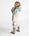 7AM rain jacket with pastel house print worn by a child, shown in a standing pose against white background.