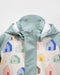 7AM rain jacket with pastel green hood and multicolor house print shown on white background.