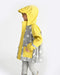 Child wearing a 7AM rain jacket in yellow and grey with star pattern, standing sideways.
