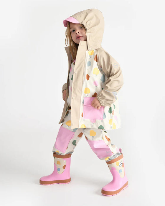 Kids rain jacket with colorful tree print and pink accents shown worn by a child indoors.