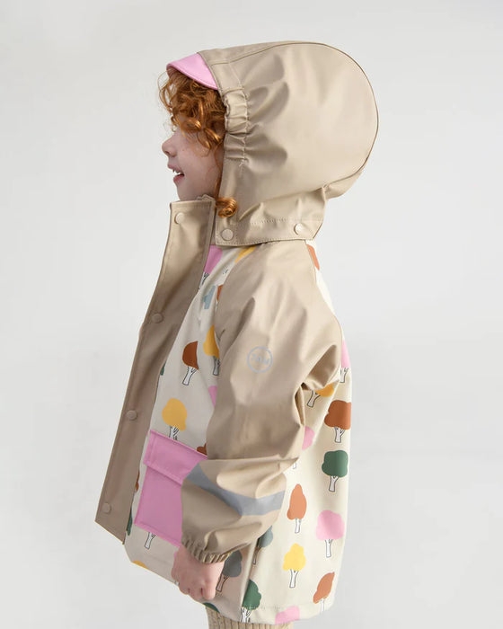 7AM rain jacket with beige hood and colorful tree pattern, worn by a child, side view.