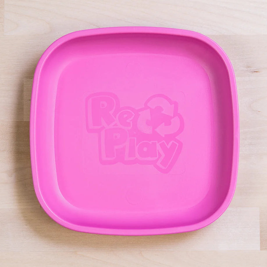 Bright pink kids' plastic plate with rounded edges on a wooden table