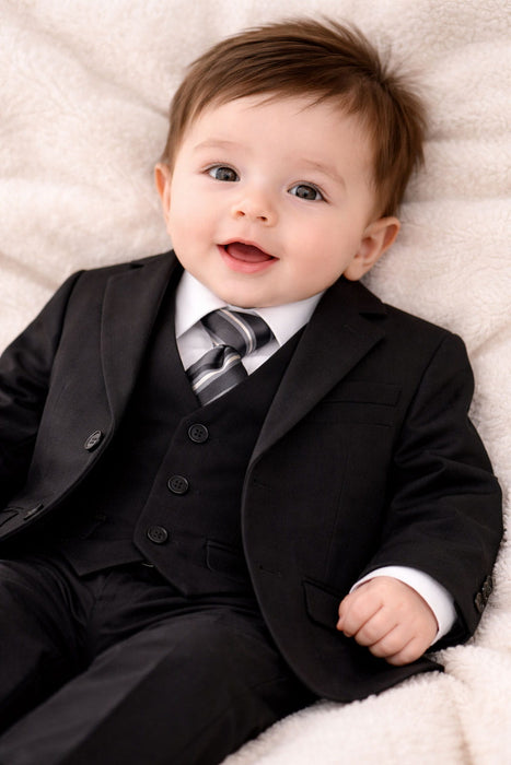 Infant smiling in a black suit with vest and striped tie, formal baby outfit