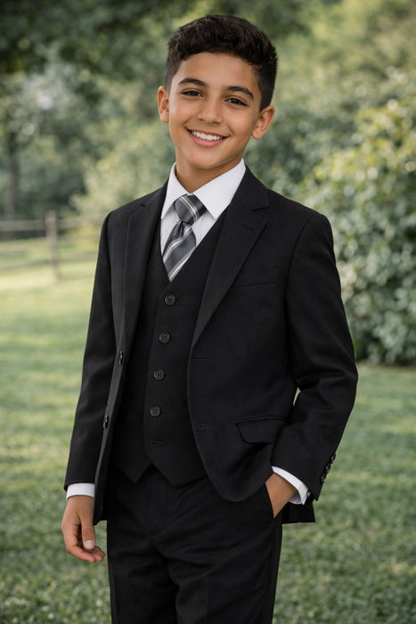 Smiling boy in a black suit and striped tie outdoors, formal kids clothing