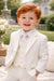 Ivory toddler suit shown on a smiling young boy outdoors, ideal for special occasions.