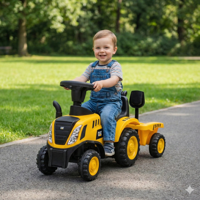 CAT ride-on toy tractor with trailer, shown with a smiling toddler on a park path.