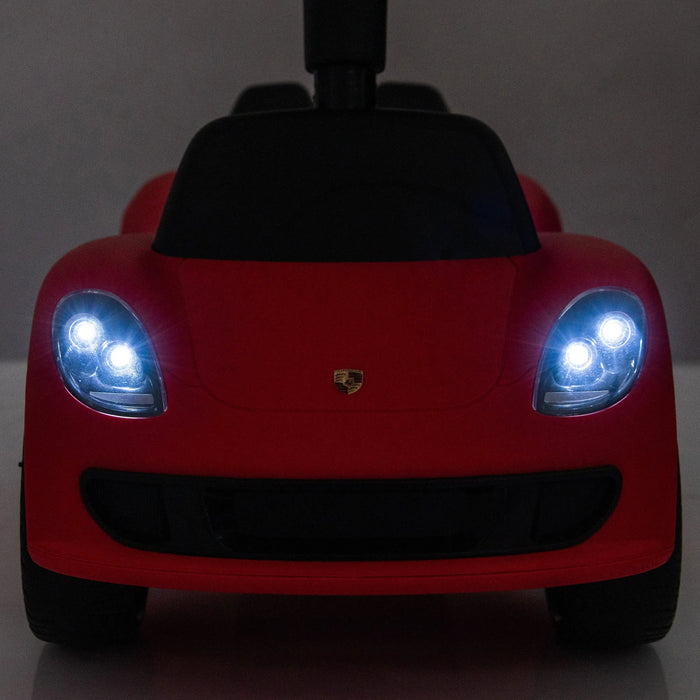 Red Porsche kids ride-on car toy with headlights turned on, front view against a plain background.