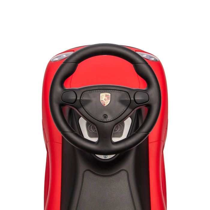 Red Porsche ride-on toy car showing the steering wheel and dashboard from above.