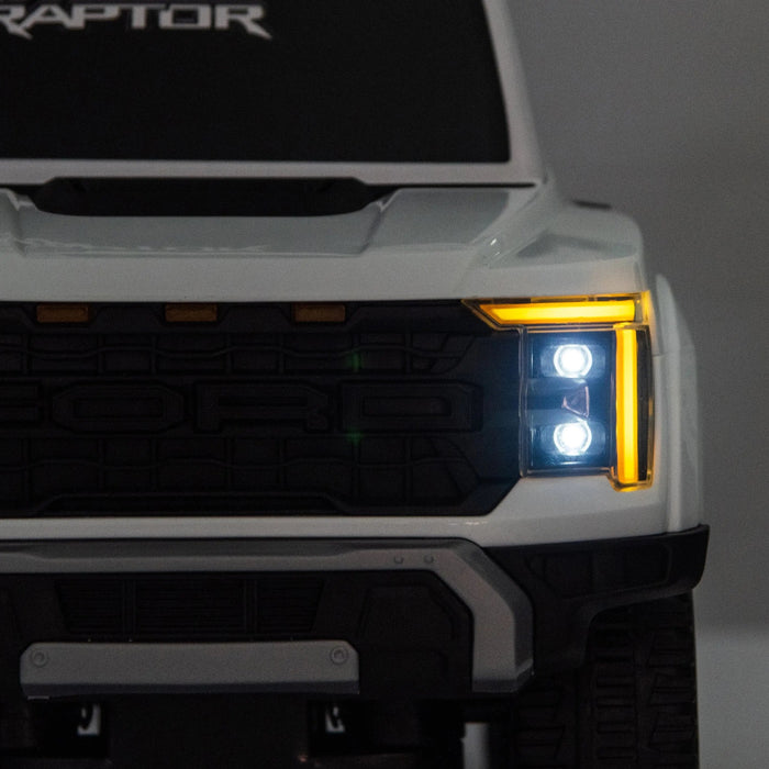 Toy Ford Raptor truck front view with illuminated LED headlights and detailed grille.
