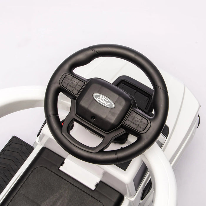 Ford kids' ride-on car steering wheel and dashboard close-up, shown from above.