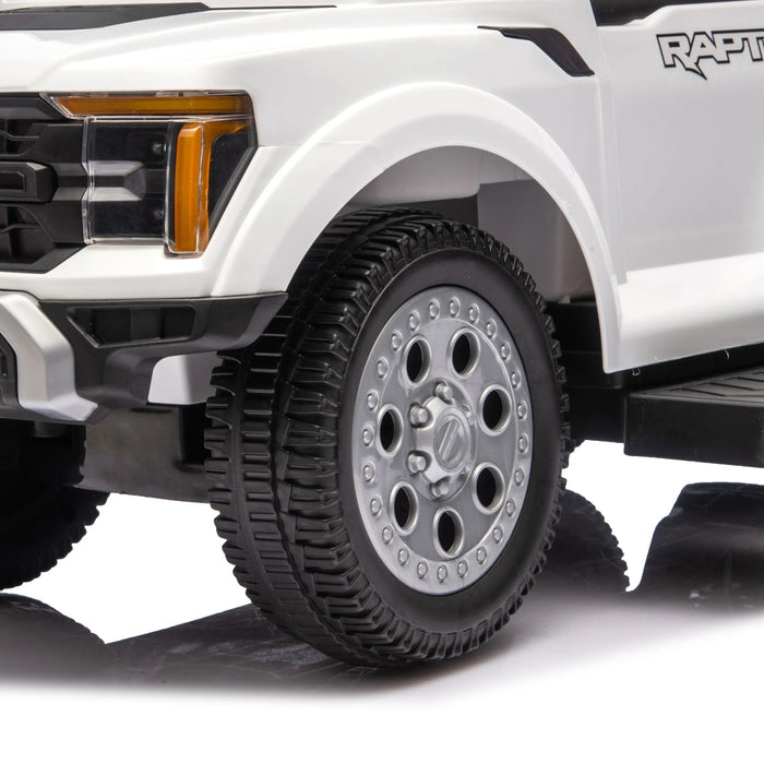 Kids ride-on Ford Raptor toy truck close-up showing detailed front wheel and off-road tire.