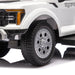 Kids ride-on Ford Raptor toy truck close-up showing detailed front wheel and off-road tire.